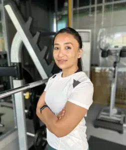 Coach Aditi Narsian standing next to a Squat Rack