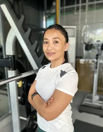 Coach Aditi Narsian standing next to a Squat Rack