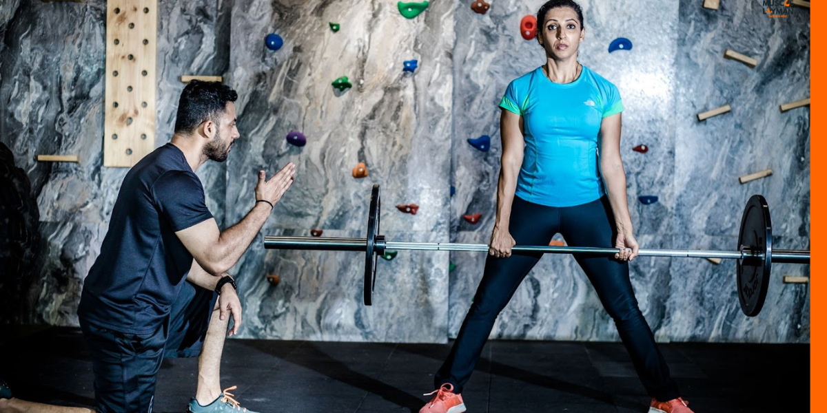 Personal trainer spotting a client for deadlit, to improve their lower body strength.