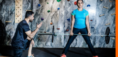 Personal trainer spotting a client for deadlit, to improve their lower body strength.