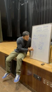 Coach Pankaj Narsian writing the law of energy balance on a whiteboard at a nutrition seminar